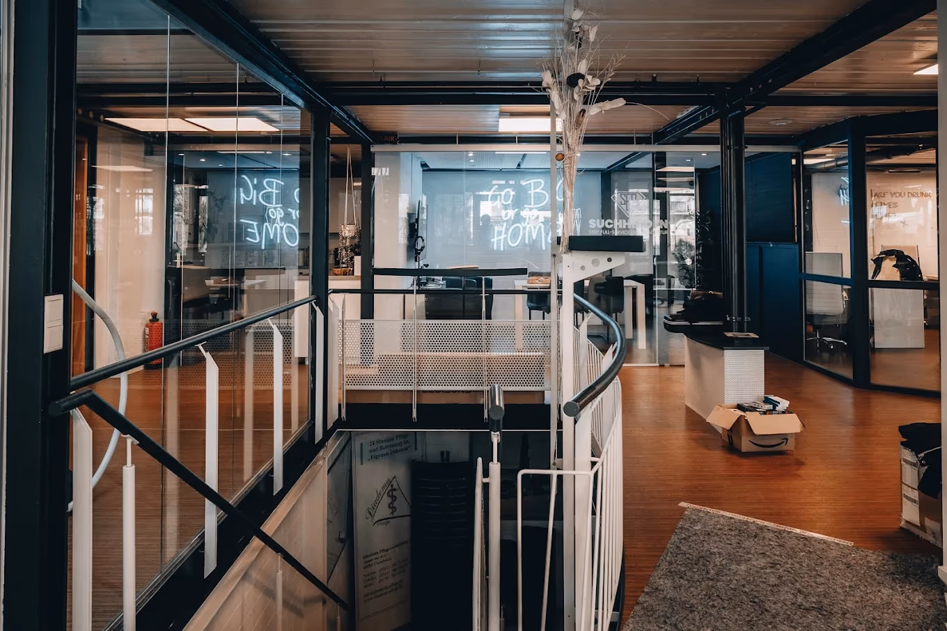 Suchhelden Office mit Glaswänden, Treppenaufgang und Go BIG or go HOME Neon-Schriftzug