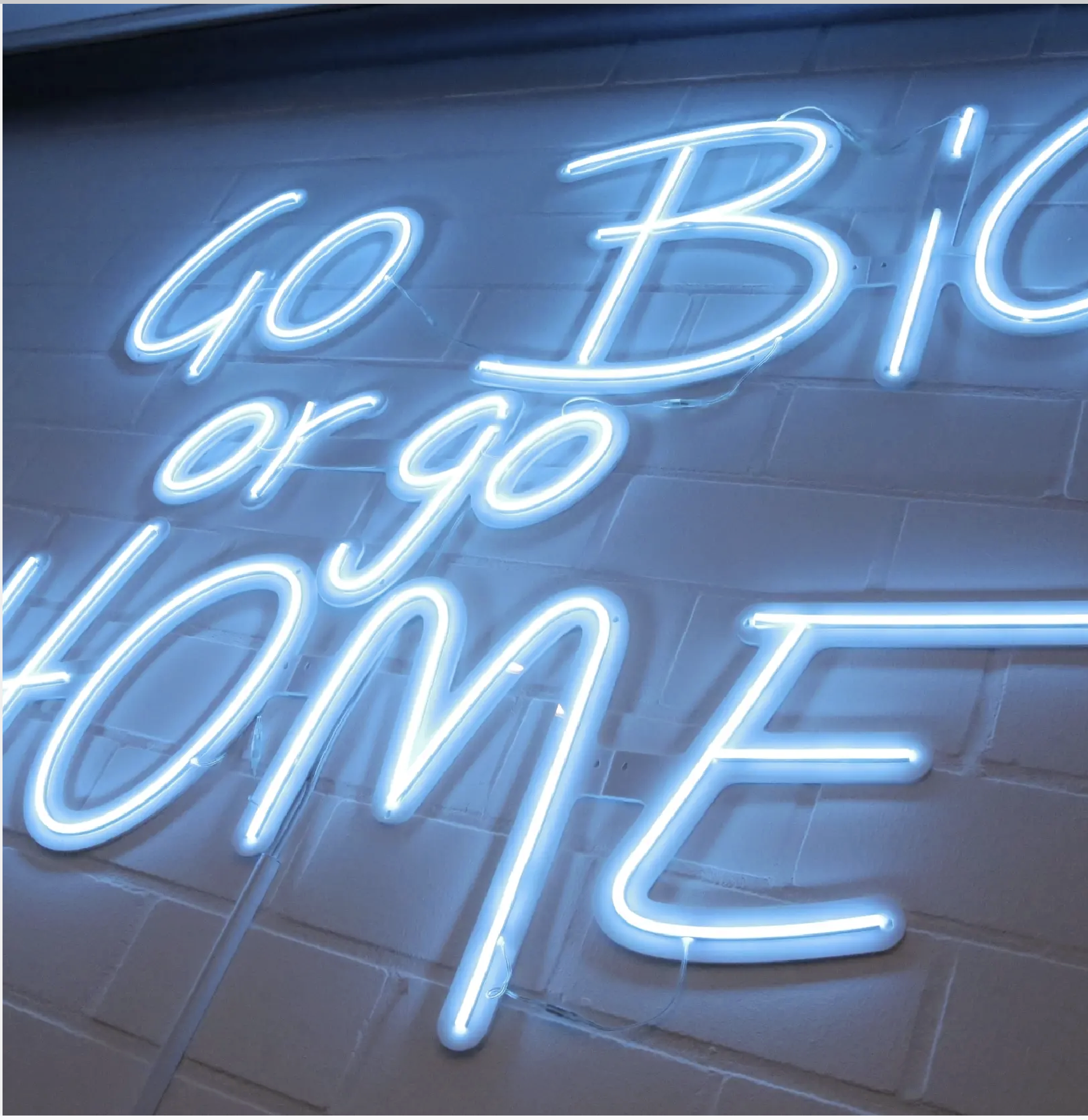 Go BIG or go HOME Neon-Schriftzug an der Bürowand der Suchhelden