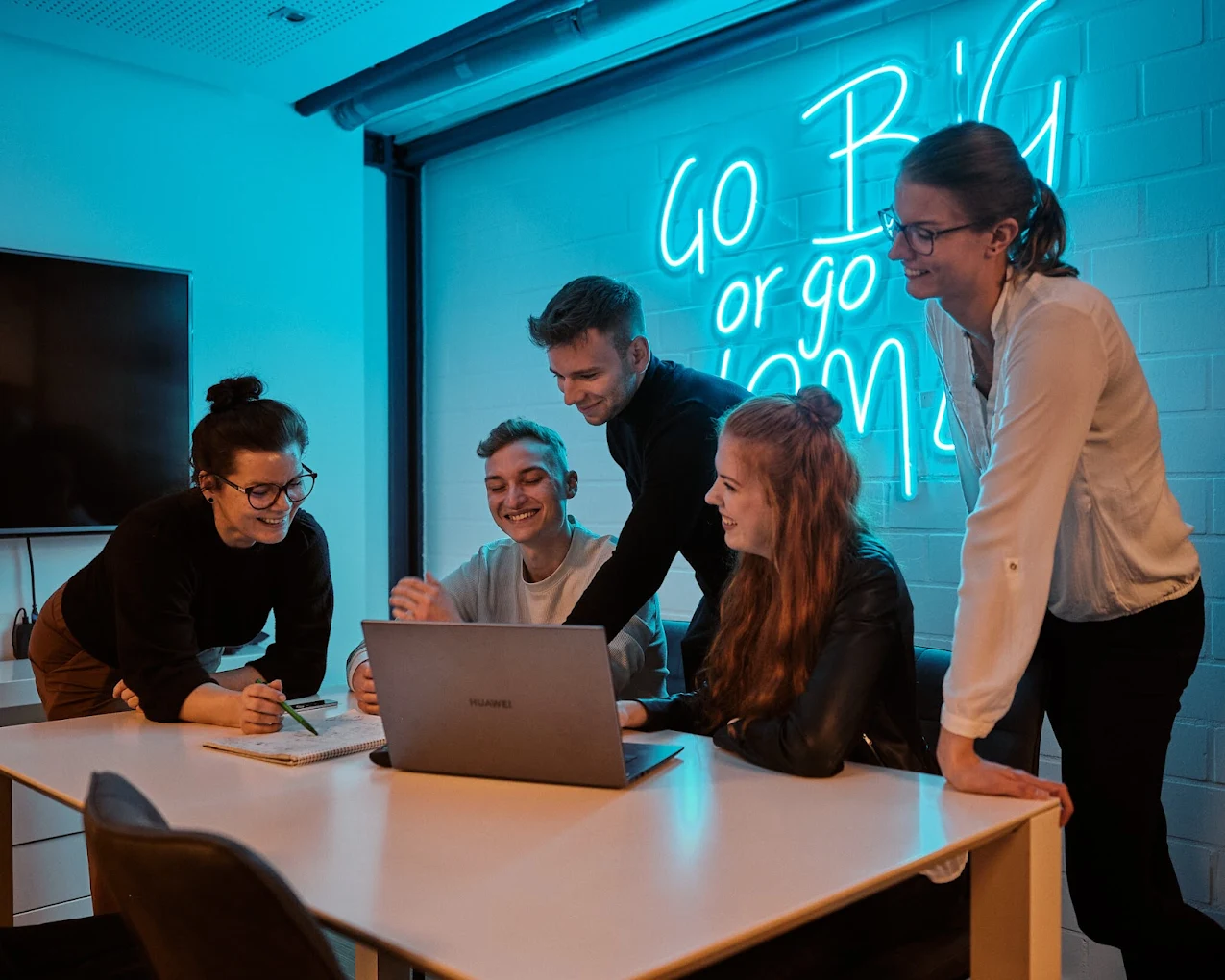 Suchhelden Team-Besprechung im Huddle-Room vor Go-Big-or-go-Home Neon-Schriftzug