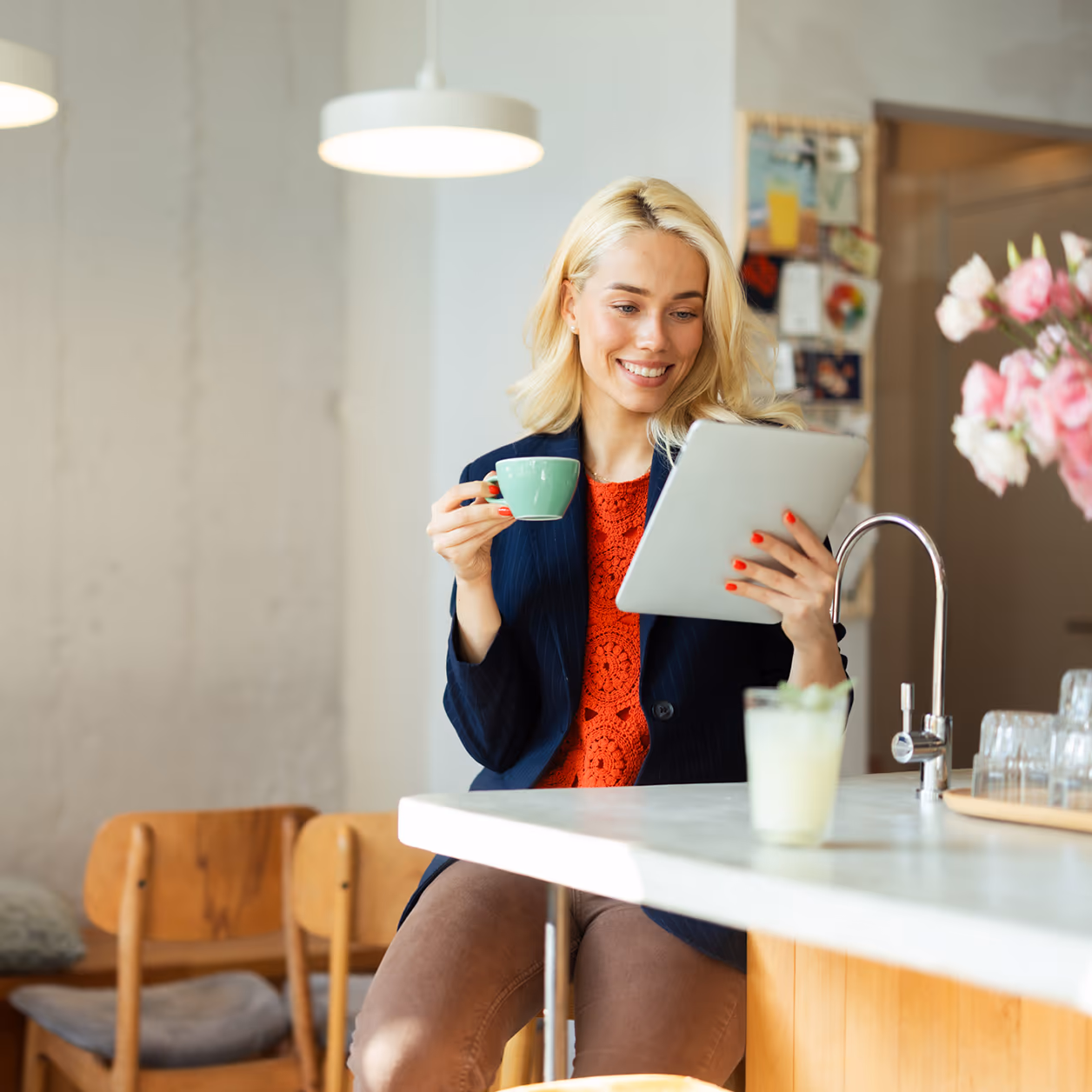 Lächelnde Geschäftsfrau, die am Tablet arbeitet und Kaffee im Café trinkt — Sinnbild für die Lifestyle-Zielgruppe