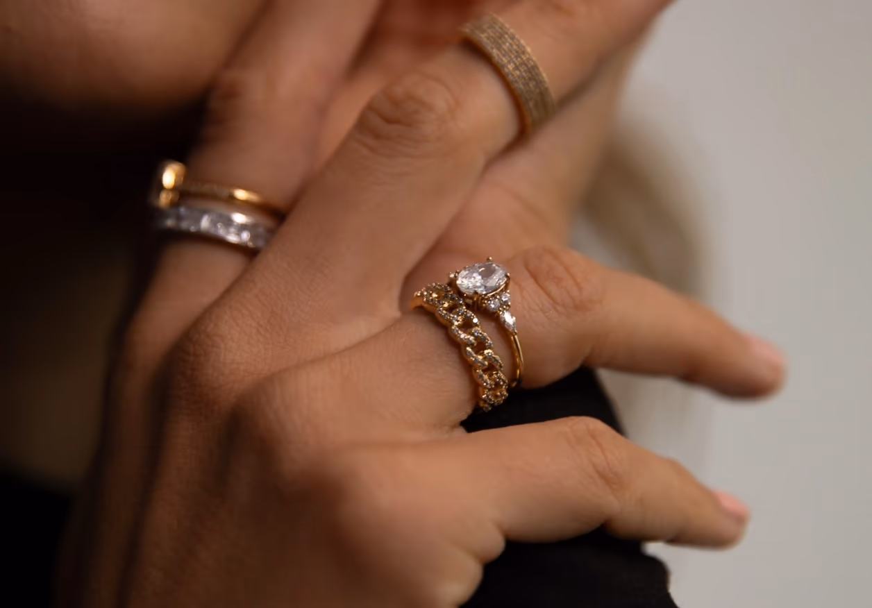 Hände mit goldenen Ringen und Schmuckarmband von Paul Valentine auf dunklem Grund